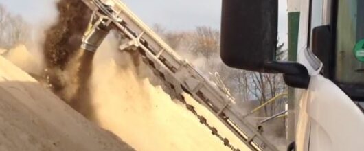 Vrachtwagenlosser lost bulkmateriaal uit walking floor oplegger